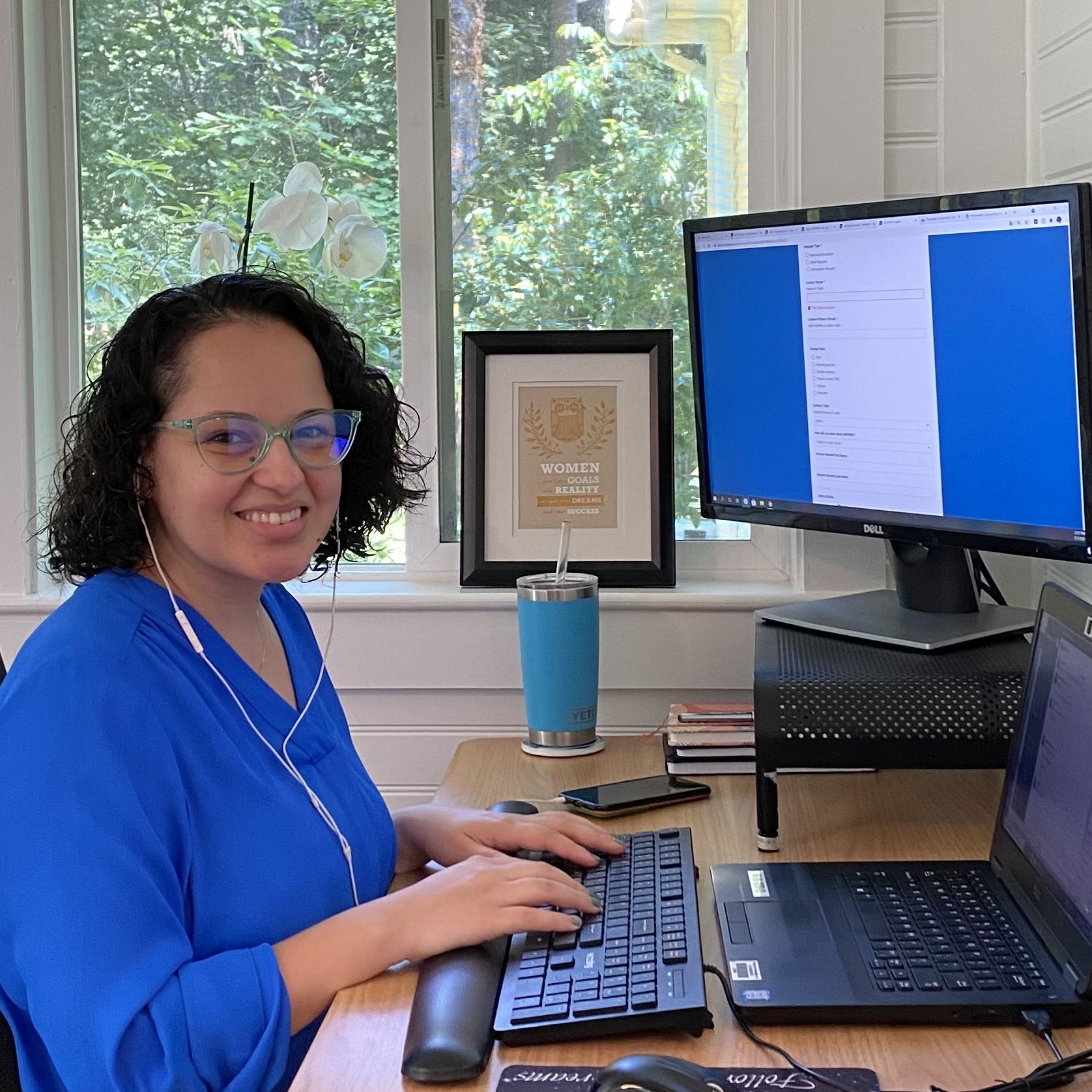 A care navigator smiles into the camera while working at a computer