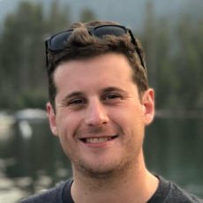 Adult with short brown hair and light skin smiles at the camera