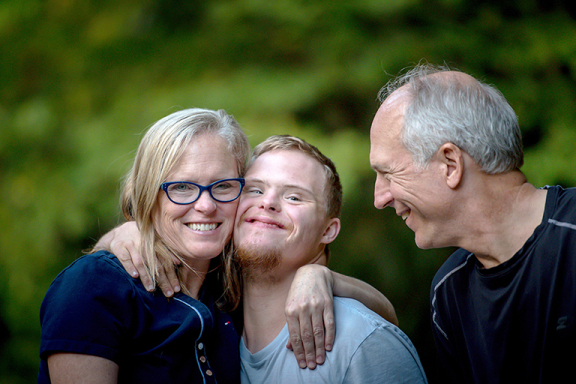 Parents hugging their adult son with down syndrome