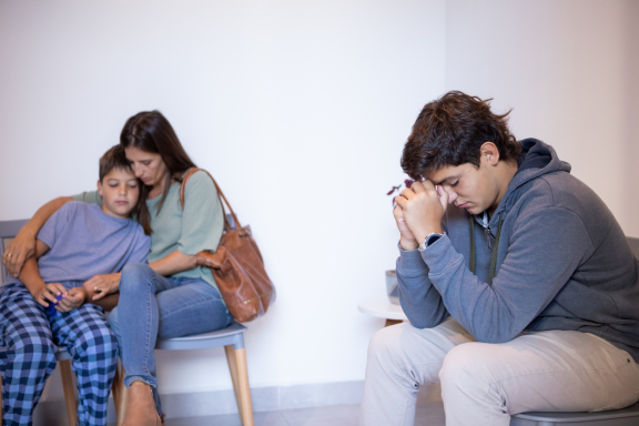 A family of three looks distraught in a waiting room
