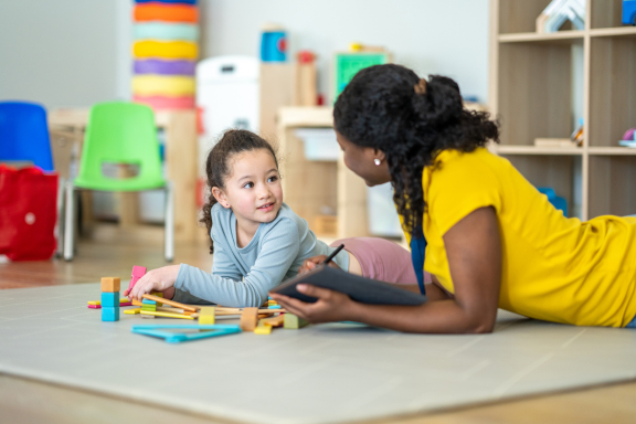 A child and therapist interact while playing on the floor together