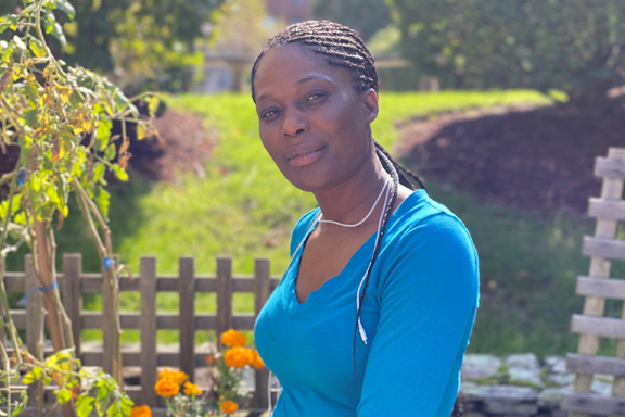 Magdalene Dessources-Osias smiling outside. She is wearing a blue shirt.