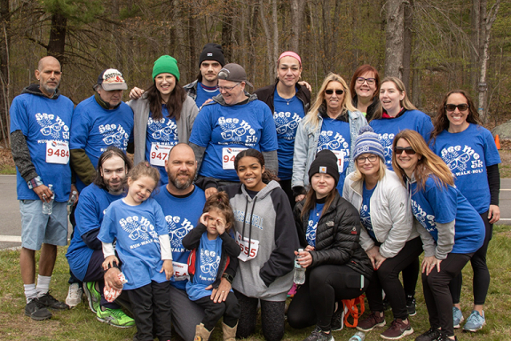 Group of several people posing and smiling at Advocates See Me 5K. They are wearing blue See Me 5K t-shirts.