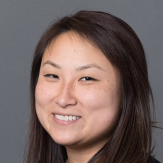 Asian young adult with long dark hair and light skin smiles at the camera
