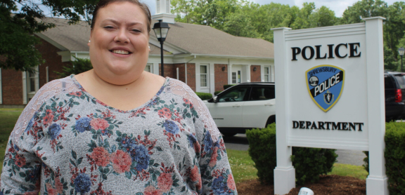 Jessica Atwood smiling standing in front of the Shrewsbury police department sign outside.