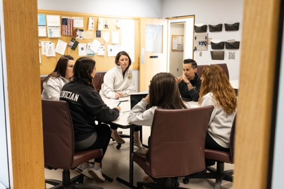 six individuals sitting at a table during a meeting