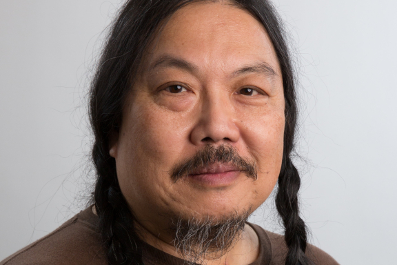 Headshot of a smiling middle-aged Asian adult with two long dark braids