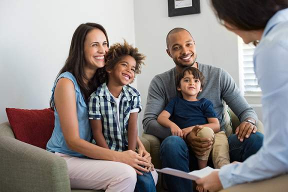 Parents and two young children speaking with a counselor