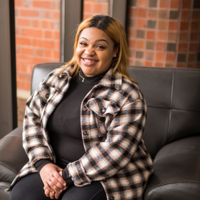 A woman sitting on a comfortable chair looking to the camera and smiling